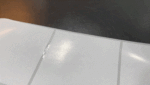Close up of white ceramic floor tiles with visible grout lines and a dark background at the top edge